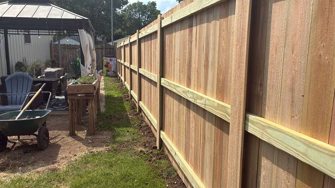 Back of a cedar privacy fence showing the rails seated into hidden U-channel steel posts